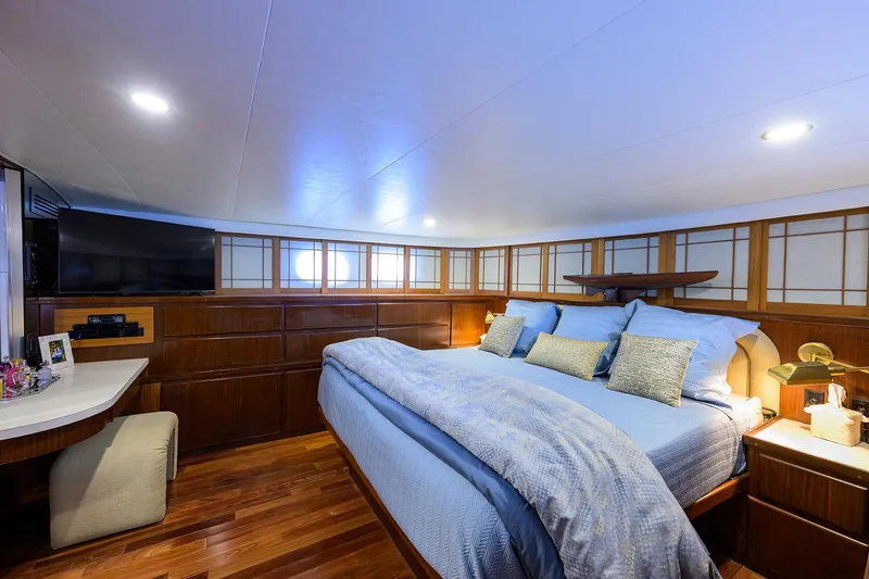Forever Young Yacht Photos Pics Luxurious bedroom interior of 1991 Hatteras 78 CMY yacht with wood paneling and cozy bedding.