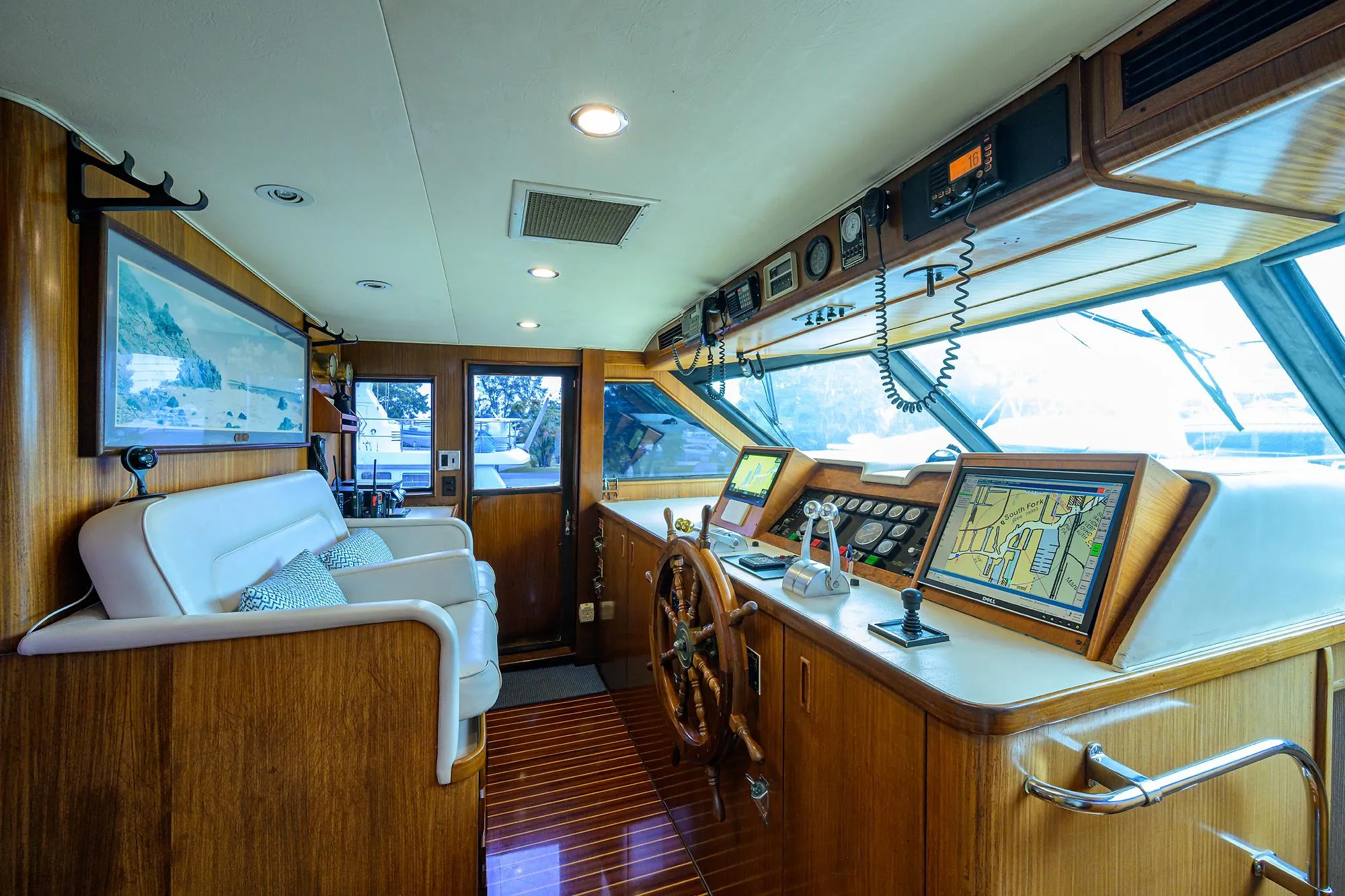 Luxurious 1991 Hatteras 78 CMY yacht interior with wooden helm, navigation equipment, and plush seating.