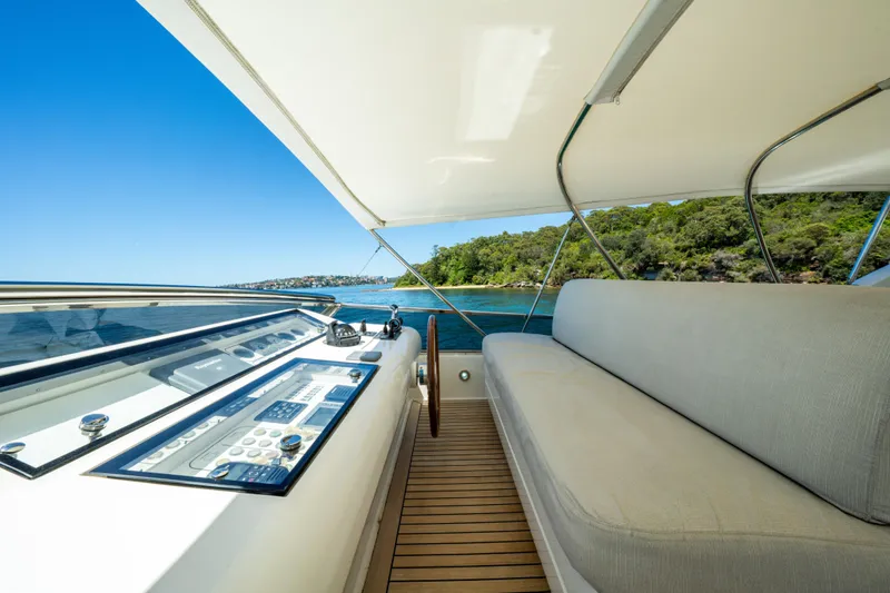 Ilyria Yacht Photos Pics Luxurious 2007 Sanlorenzo SL72 yacht deck with seating and control panel, cruising near lush coastline.