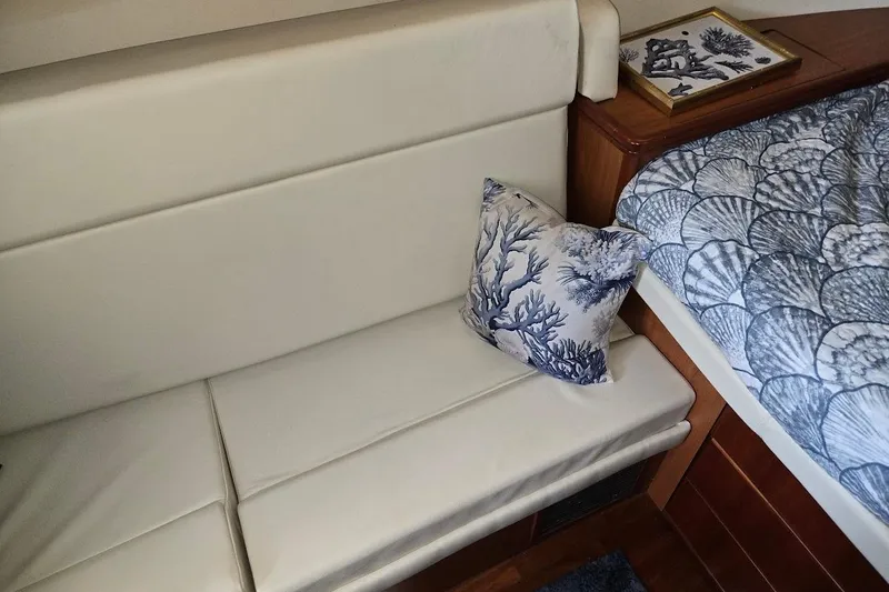 Bay'be Yacht Photos Pics 2009 Mainship Pilot 31 interior with white seating, nautical pillow, and shell-patterned bedding.