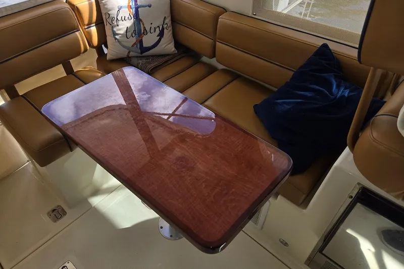 Bay'be Yacht Photos Pics Interior of 2009 Mainship Pilot 31 with wooden table and cushioned seating.