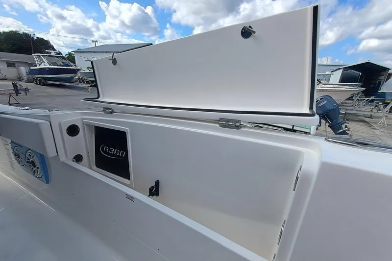 360-105 Yacht Photos Pics 2026 Robalo R360 Center Console boat with open storage compartment, docked under a cloudy sky.