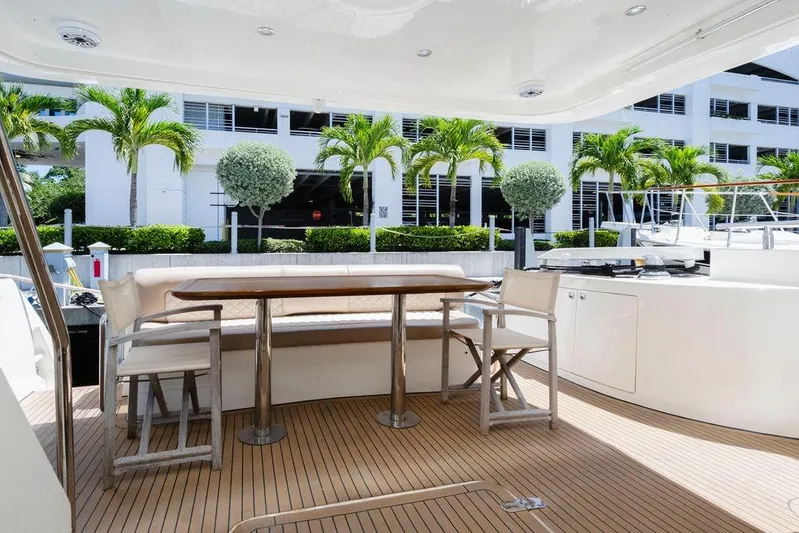 Voluptas Yacht Photos Pics Luxurious 2006 Aicon Flybridge yacht deck with seating, table, and tropical backdrop.