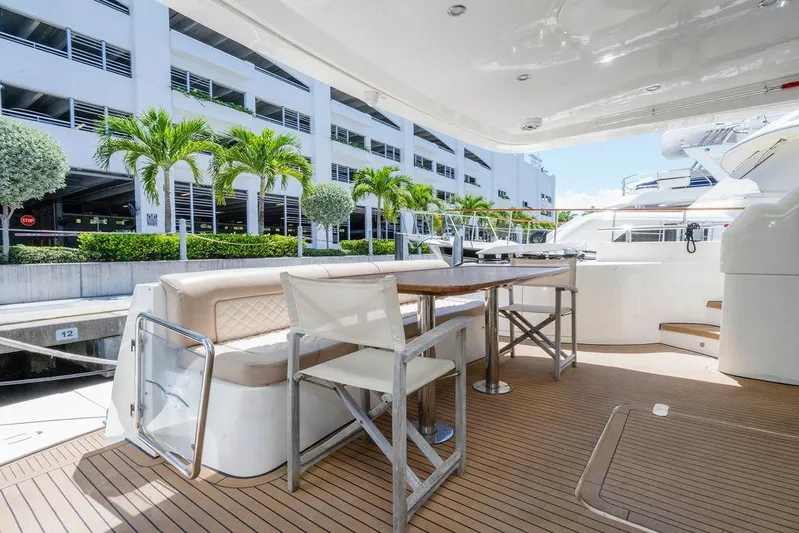 Voluptas Yacht Photos Pics Luxurious 2006 Aicon Flybridge yacht deck with seating and dining area, docked near palm trees.