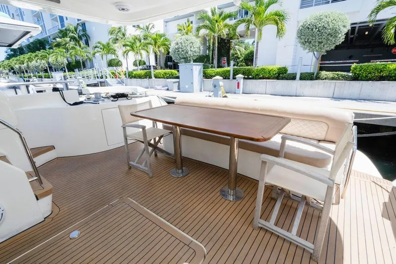 Voluptas Yacht Photos Pics Luxury 2006 Aicon Flybridge yacht deck with seating and table, surrounded by palm trees.
