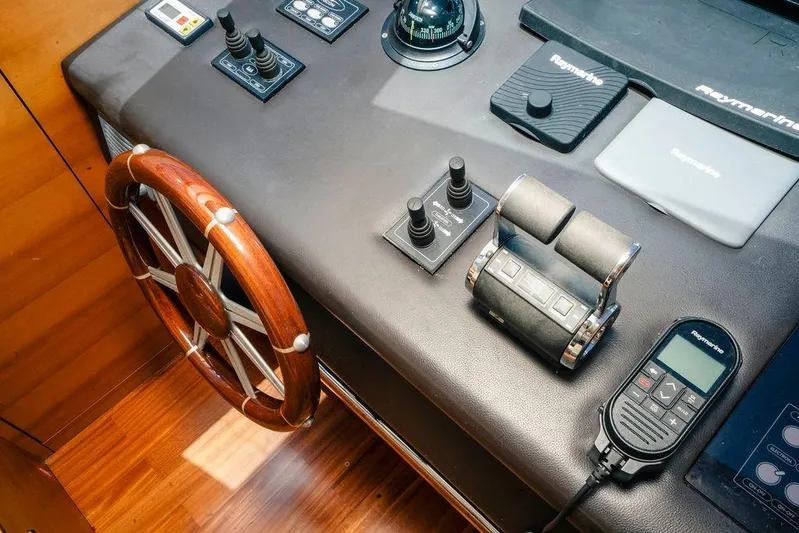 Voluptas Yacht Photos Pics Control panel of 2006 Aicon Flybridge yacht with wooden steering wheel and navigation equipment.