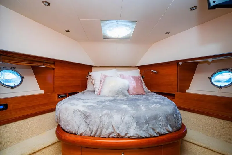 Voluptas Yacht Photos Pics Luxurious 2006 Aicon Flybridge yacht bedroom with cozy round bed and elegant wood paneling.