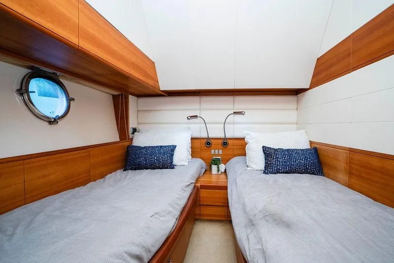 Voluptas Yacht Photos Pics Twin cabin interior of 2006 Aicon Flybridge yacht with wooden accents and porthole.