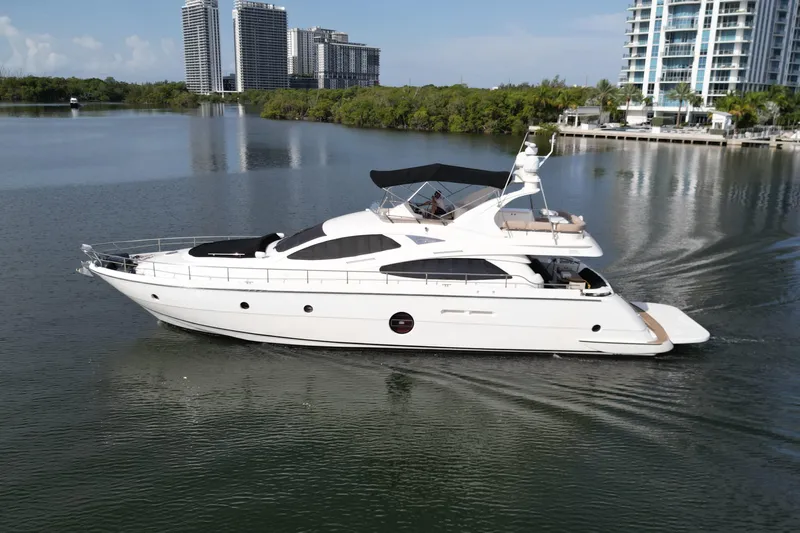 Voluptas Yacht Photos Pics 2006 Aicon Flybridge yacht cruising on calm waters near modern high-rise buildings.
