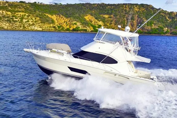  Yacht Photos Pics 2012 Riviera Convertible yacht cruising on blue waters near a rocky coastline.