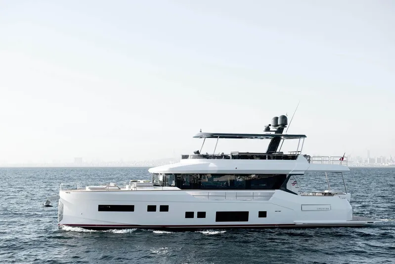  Yacht Photos Pics 2024 Sirena 68 yacht cruising on open sea with city skyline in background.