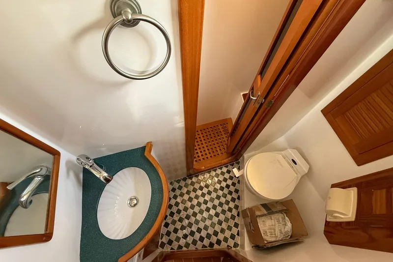 Sarah Yacht Photos Pics Compact bathroom in 2000 Cabo Rico Cutter 45 yacht with sink, toilet, and checkered floor.