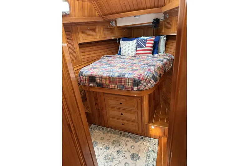 Sarah Yacht Photos Pics Cozy cabin interior of 2000 Cabo Rico Cutter 45 with wooden finish and plaid bedding.