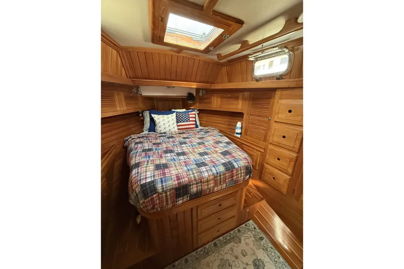 Sarah Yacht Photos Pics Cozy cabin interior of 2000 Cabo Rico Cutter 45 with wooden finish and plaid bedding.