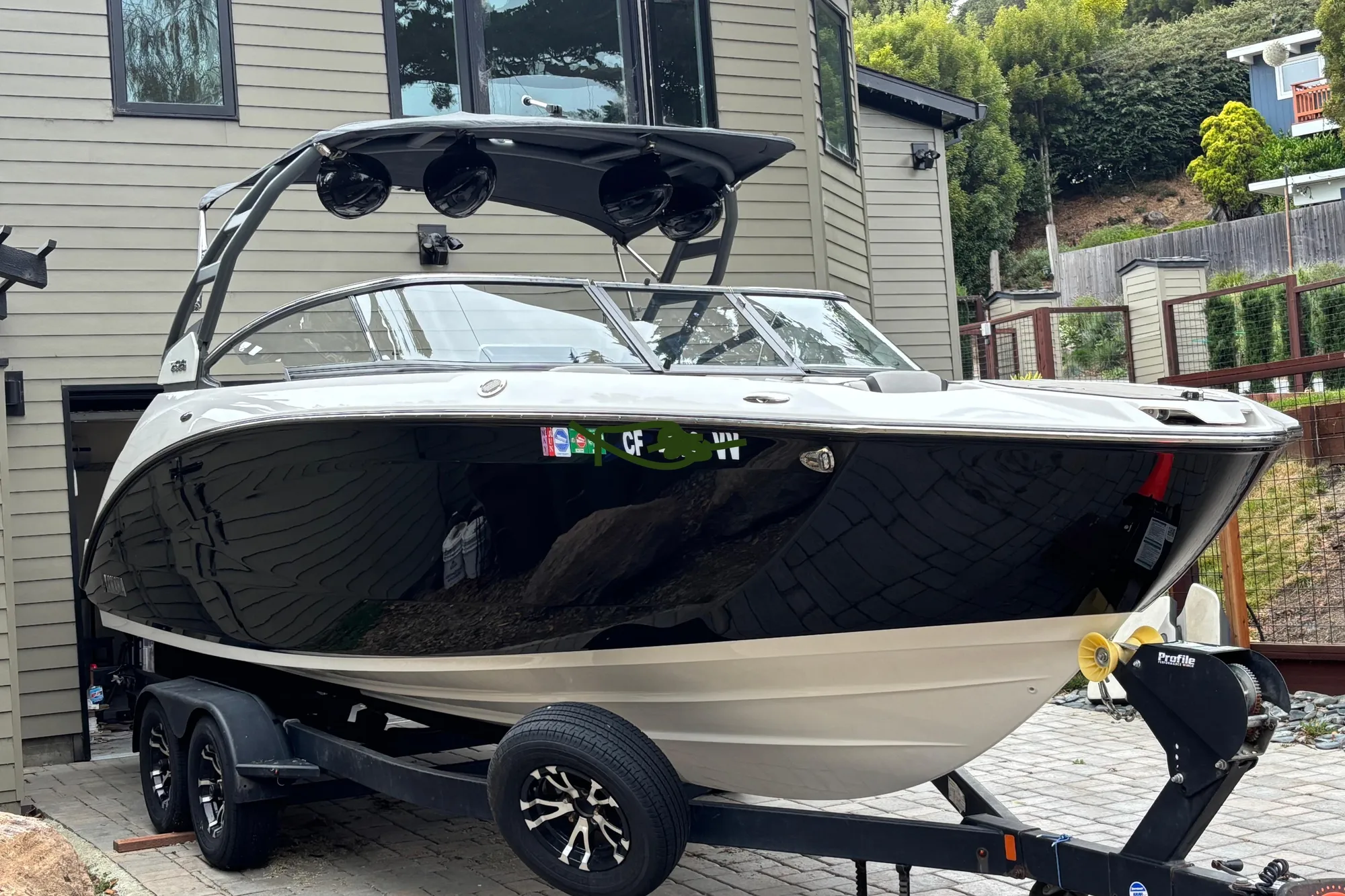 2022 Yamaha Boats 252S on trailer, parked near modern house, surrounded by greenery.