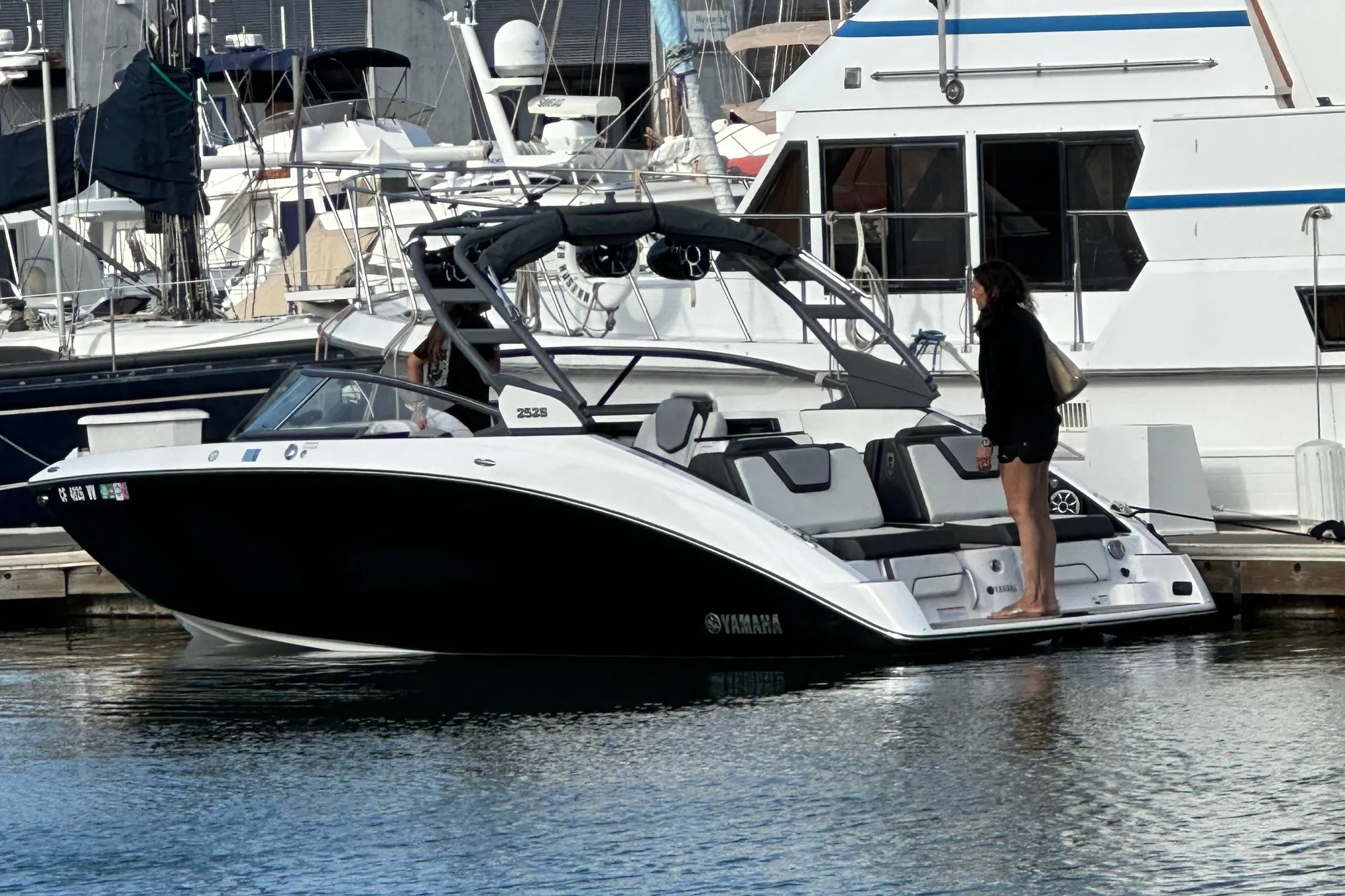 2022 Yamaha Boats 252S docked at marina with person standing on deck.