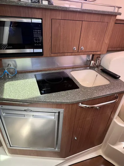  Yacht Photos Pics Compact kitchen area in a 2016 Boston Whaler 315 Conquest boat with stove, sink, and microwave.