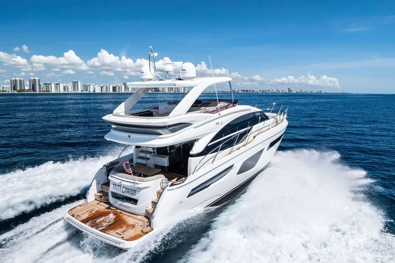 Salty Cowboy Yacht Photos Pics Luxurious 2022 Princess 55 Flybridge yacht cruising on open sea with city skyline backdrop.
