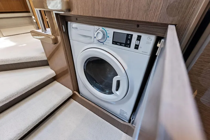 Salty Cowboy Yacht Photos Pics Built-in washing machine on 2022 Princess 55 Flybridge yacht, near carpeted stairs.