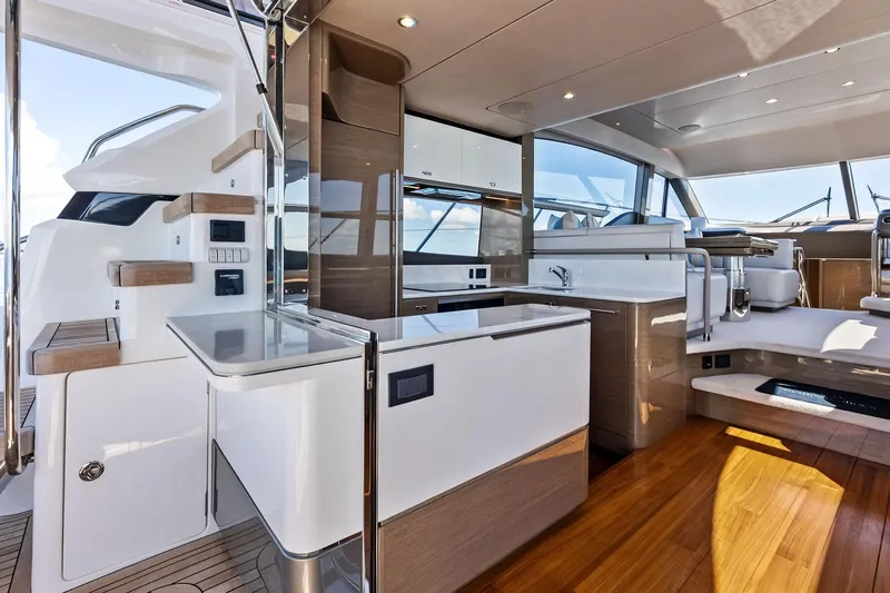 Salty Cowboy Yacht Photos Pics Luxurious interior of 2022 Princess 55 Flybridge yacht with modern kitchen and seating area.