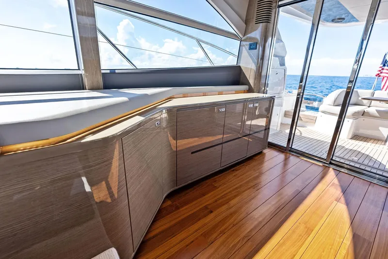 Salty Cowboy Yacht Photos Pics Luxurious interior of 2022 Princess 55 Flybridge yacht with ocean view and sleek wood finish.