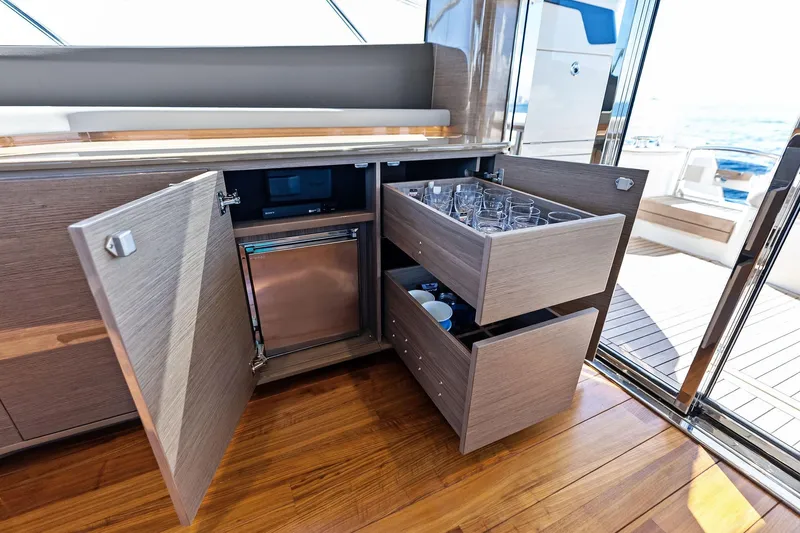 Salty Cowboy Yacht Photos Pics Luxurious interior of 2022 Princess 55 Flybridge yacht with open cabinets and drawers.