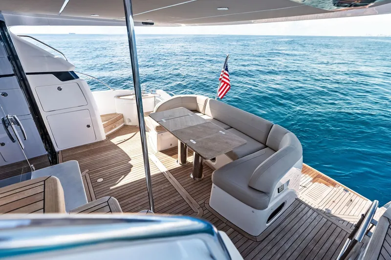 Salty Cowboy Yacht Photos Pics Luxurious 2022 Princess 55 Flybridge yacht with elegant seating, ocean view, and American flag.