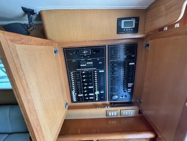  Yacht Photos Pics Electrical panel inside a 2007 Jersey Cape 44 CNV boat with open wooden cabinet doors.