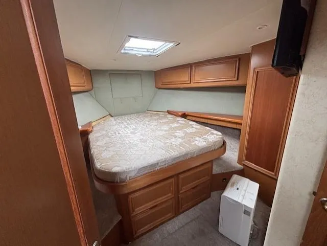  Yacht Photos Pics 2007 Jersey Cape 44 CNV cabin interior with bed and wooden storage cabinets.
