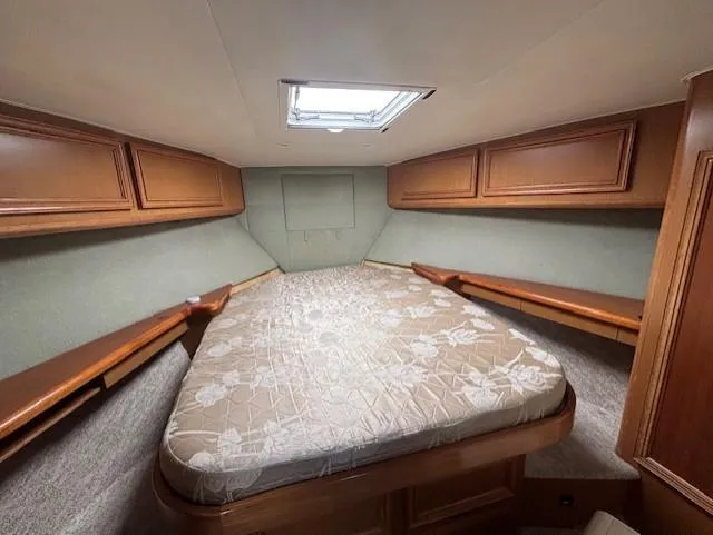  Yacht Photos Pics 2007 Jersey Cape 44 CNV cabin interior with bed and wooden storage cabinets.