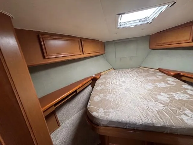  Yacht Photos Pics 2007 Jersey Cape 44 CNV cabin interior with bed and wooden storage cabinets.