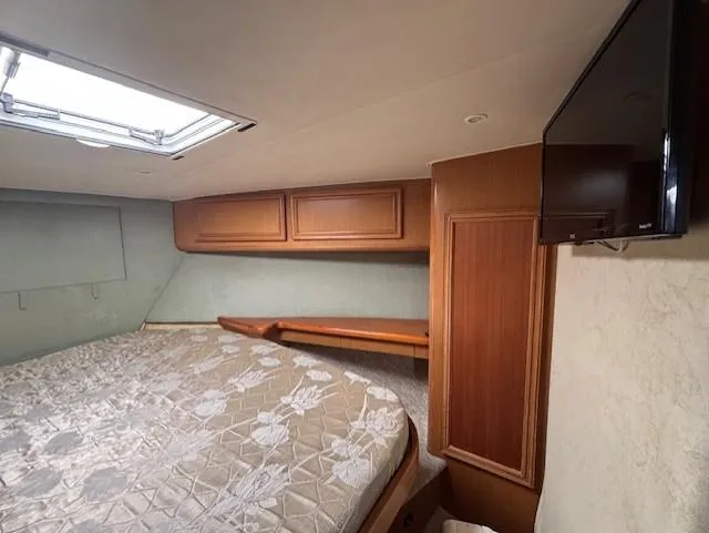  Yacht Photos Pics Interior of 2007 Jersey Cape 44 CNV boat with bed, wooden cabinets, and TV.