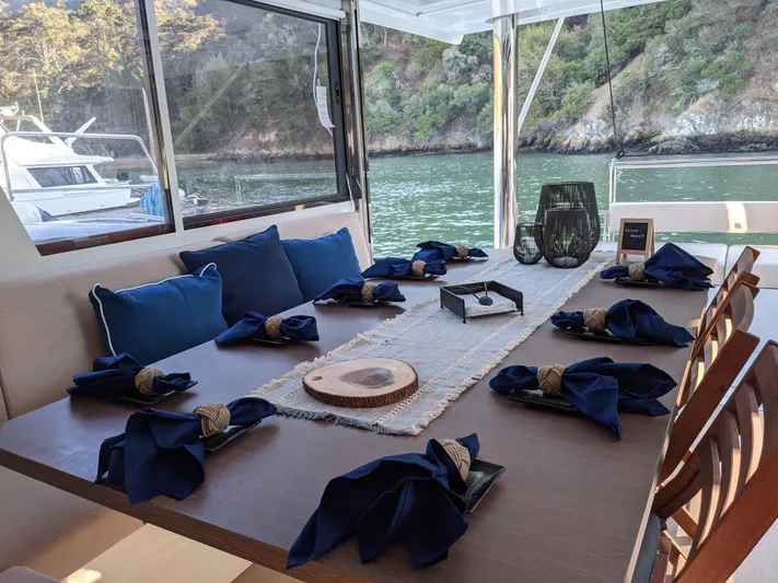 Blureverie Yacht Photos Pics Elegant dining setup on a Bali 4.8 yacht, featuring blue napkins and scenic water views.