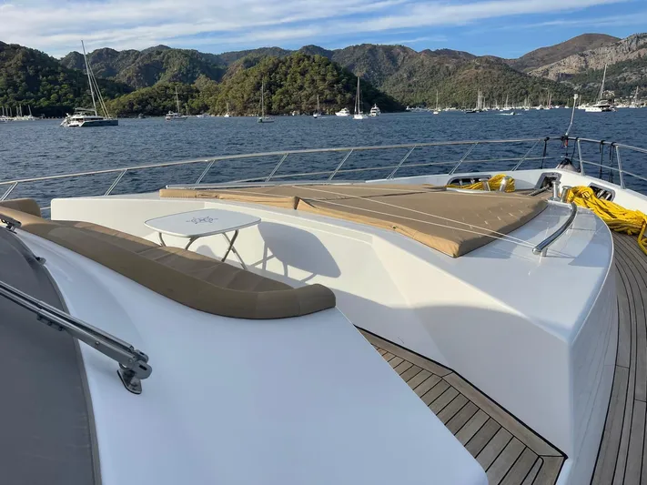 Tmr Yacht Photos Pics Luxury yacht deck with sun loungers, table, and scenic mountain view.