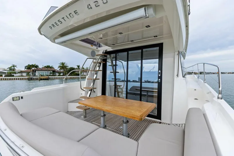 So Fly Yacht Photos Pics Luxury 2022 Prestige 420 yacht with outdoor seating and table, docked by waterfront homes.