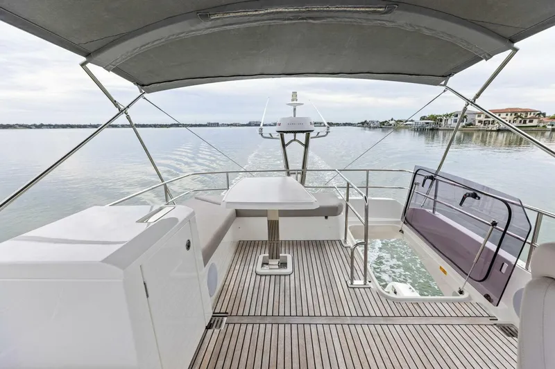 So Fly Yacht Photos Pics 2022 Prestige 420 yacht deck with seating, table, and canopy on calm water.