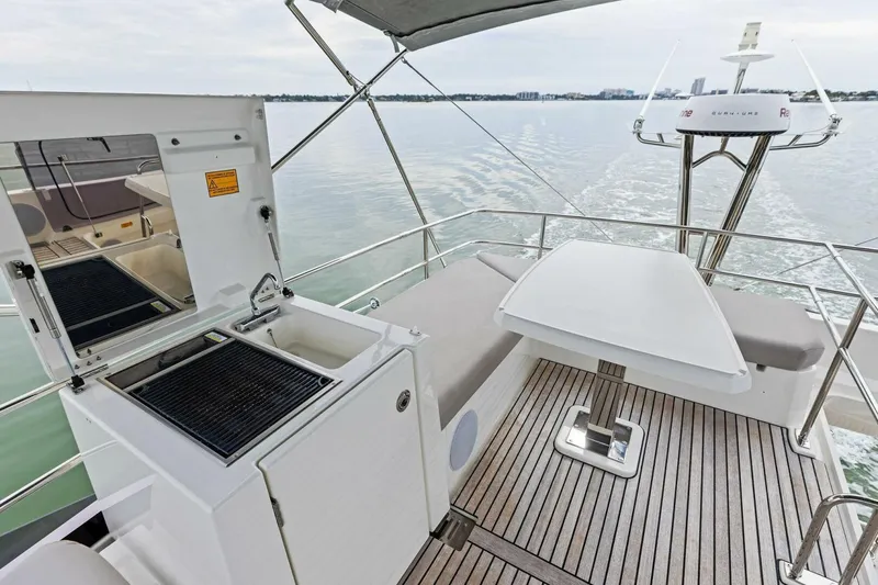 So Fly Yacht Photos Pics 2022 Prestige 420 yacht deck with grill, table, and seating on calm water.