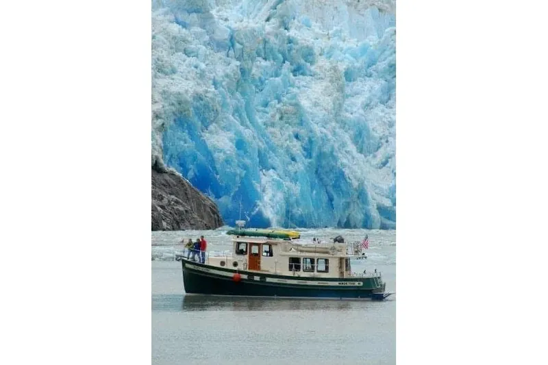 Green Goose Yacht Photos Pics Nordic Tug 42 (1998) cruising near a stunning blue glacier backdrop.