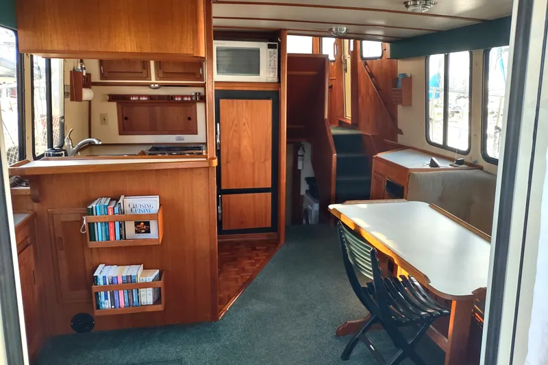 Green Goose Yacht Photos Pics Interior of 1998 Nordic Tug 42, featuring kitchen, dining area, and wooden cabinetry.