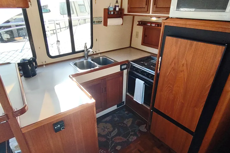 Green Goose Yacht Photos Pics 1998 Nordic Tug 42 interior kitchen with wooden cabinetry, stove, and double sink.