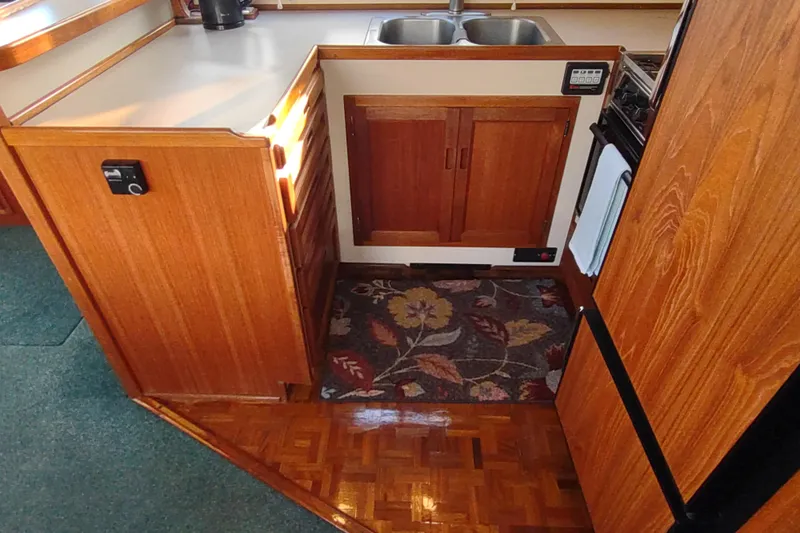 Green Goose Yacht Photos Pics 1998 Nordic Tug 42 interior kitchen with wooden cabinets and floral rug.