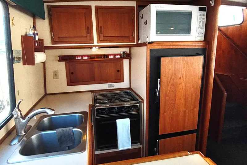 Green Goose Yacht Photos Pics 1998 Nordic Tug 42 galley with wooden cabinets, stove, microwave, and double sink.