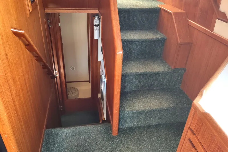 Green Goose Yacht Photos Pics Interior stairs of 1998 Nordic Tug 42 with wooden paneling and carpeted steps.