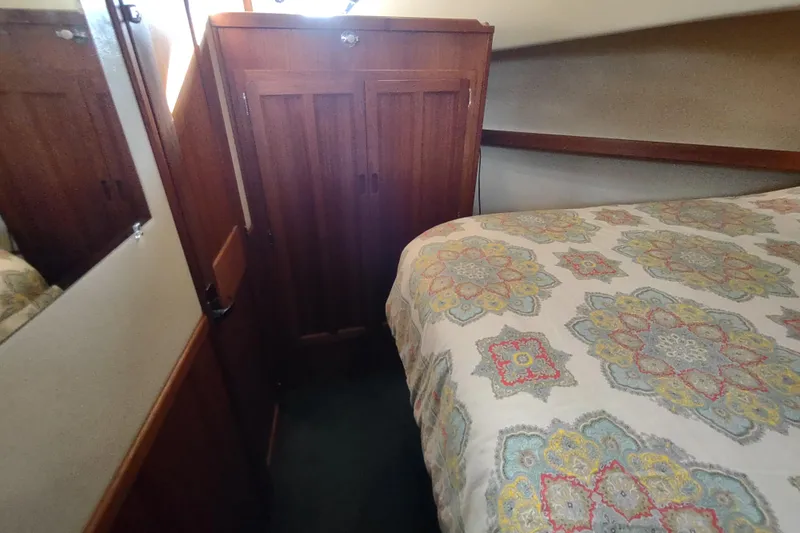 Green Goose Yacht Photos Pics Cozy cabin interior of 1998 Nordic Tug 42 with patterned bedding and wooden wardrobe.