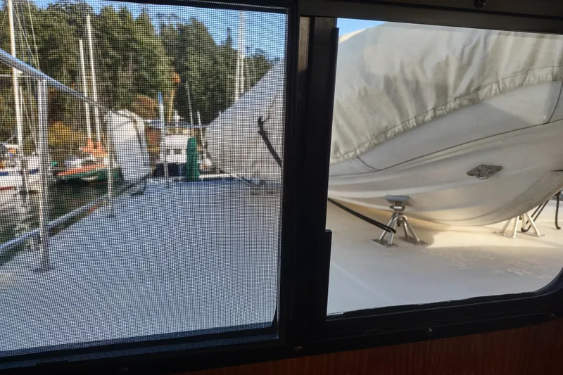 Green Goose Yacht Photos Pics 1998 Nordic Tug 42 deck view through window, featuring docked boats and trees.