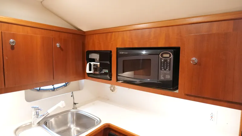 Extremely Clean Boat Yacht Photos Pics 2000 Tiara Yachts 3700 Open kitchen with microwave, sink, and wooden cabinets.