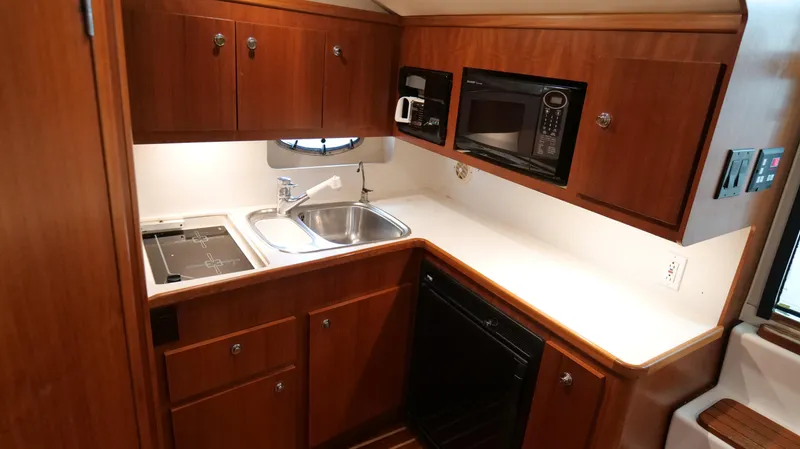 Extremely Clean Boat Yacht Photos Pics Compact kitchen in 2000 Tiara Yachts 3700 Open, featuring wood cabinets and modern appliances.