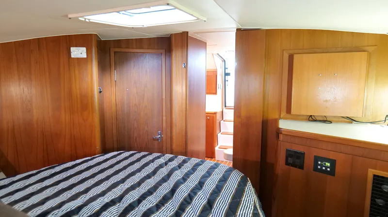 Extremely Clean Boat Yacht Photos Pics Interior cabin of 2000 Tiara Yachts 3700 Open, featuring wood paneling and striped bedding.