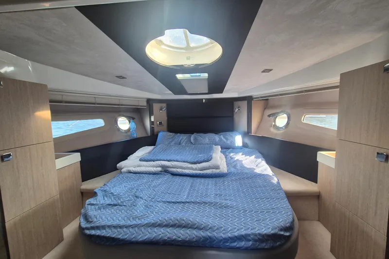  Yacht Photos Pics Luxurious cabin interior of 2015 Cranchi M 44 HT yacht with cozy bed and porthole windows.