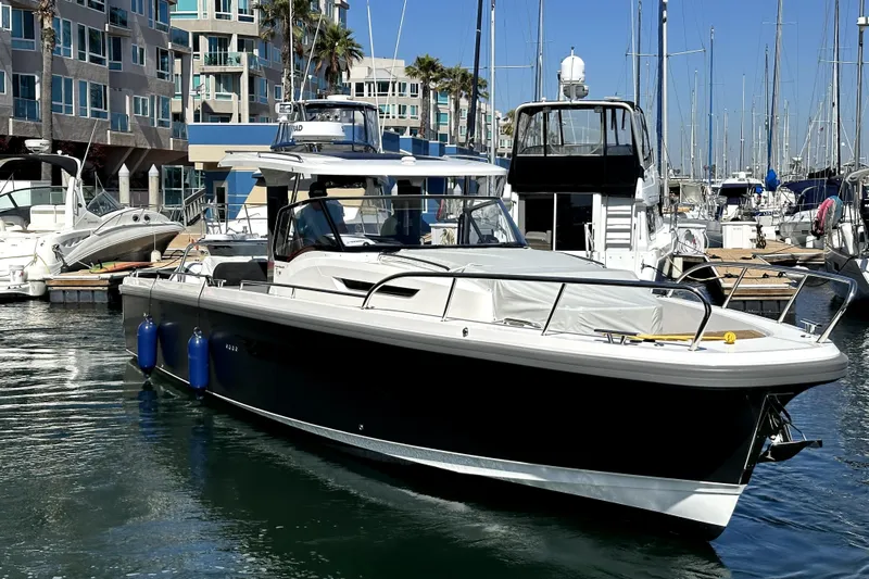 Mdr #187 In Stock Yacht Photos Pics 2023 Nimbus T11 boat docked in a marina with modern buildings in the background.
